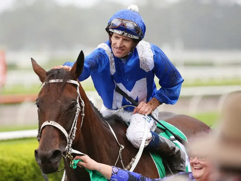 Jockey Hugh Bowman pats the head of Winx