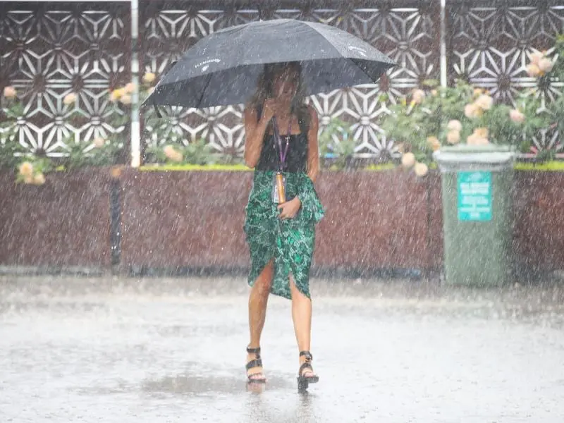 A racegoer holds an umbrella in the heavy rain